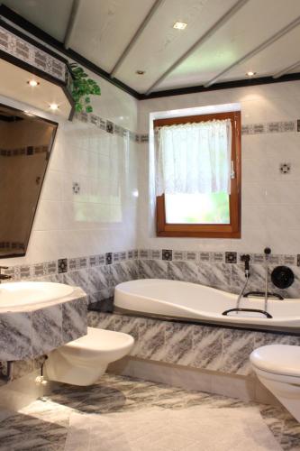 a bathroom with two toilets and a tub and a sink at Haus Kofler in Casateia
