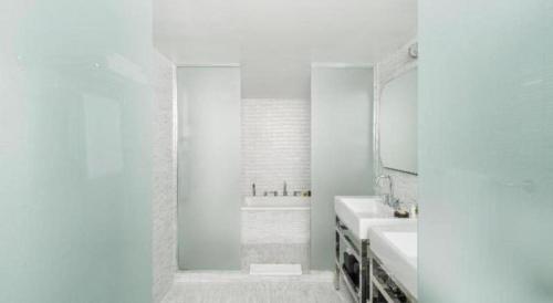 une salle de bain blanche avec deux lavabos et un miroir dans l'établissement COMO Metropolitan Miami Beach, à Miami Beach