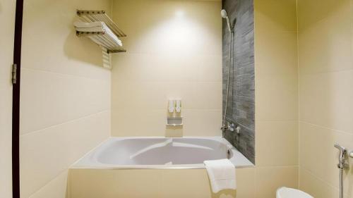 a white bathroom with a tub and a toilet at Pinehurst Golf Club and Hotel in Ban Bang Khan