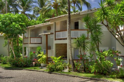 a building with palm trees in front of it at Saint Tropez Praia Hotel in Arraial d'Ajuda