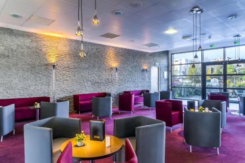 a room with tables and chairs and a brick wall at Best Western Plus Paris Velizy in Vélizy-Villacoublay