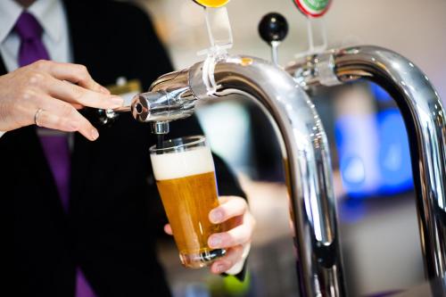 a man in a suit drinking a beer from a faucet at Best Western Plus Paris Velizy in Vélizy-Villacoublay