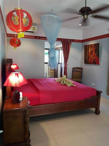 a bedroom with a red bed and a ceiling fan at phu petra villa in Ao Nang 