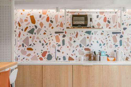 een keuken met een magnetron op een aanrecht bij Sweetly Isatis Mérignac Hôtel de ville in Mérignac