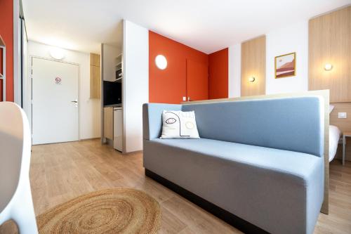 een woonkamer met een blauwe bank en oranje muren bij Sweetly Isatis Mérignac Hôtel de ville in Mérignac