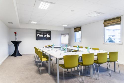 a conference room with a long table and yellow chairs at Best Western Plus Paris Velizy in Vélizy-Villacoublay