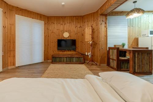 een slaapkamer met een bed en een tv aan een houten muur bij 감성제주스테이 in Songnang-dong