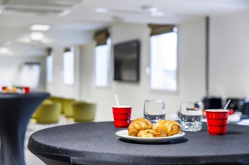 a plate of donuts on a table with two glasses at Best Western Plus Paris Velizy in Vélizy-Villacoublay