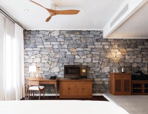 a room with a stone wall with a microwave at Hotel Kiridara Luang Prabang in Luang Prabang