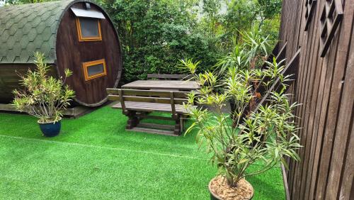 een tuin met een houten bank en een hobbithuisje bij Mini Hotel Übernachten Im Gurkenfass in Lübbenau