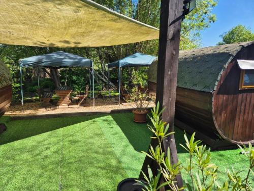 een tuin met een rieten dak en een grasveld bij Mini Hotel Übernachten Im Gurkenfass in Lübbenau