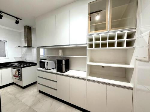 une cuisine blanche avec des armoires blanches et un micro-ondes dans l'établissement Apartmento com 3 dorm no Canto do Forte, à Praia Grande