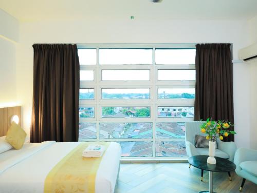 a bedroom with a large window and a bed and a chair at BIG TREE HOTEL in Temerloh