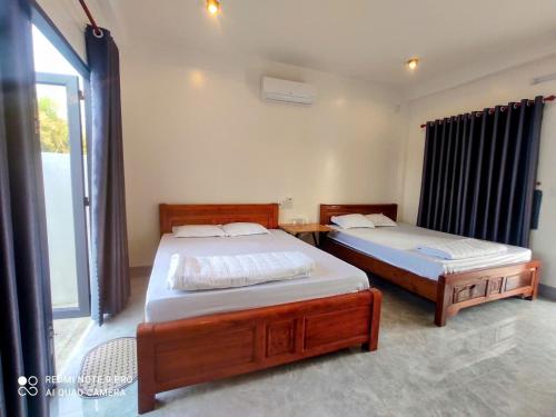 a bedroom with two beds and a large window at Nest Homestay in Cat Tien