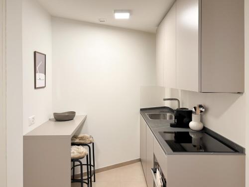 a kitchen with white cabinets and a black counter top at Studio in central Crans-Montana in Crans-Montana