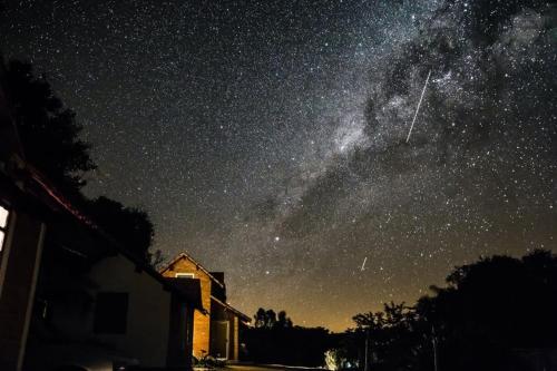 una vista nocturna de la Vía Láctea y una casa en Pousada Shangrilá São Thomé, en São Thomé das Letras