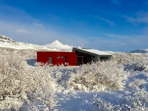 a red building in the snow with a mountain in the background at Nes in Bifrost