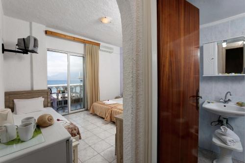 een hotelkamer met een badkamer met een bed en een wastafel bij Zorbas Hotel in Chersonissos