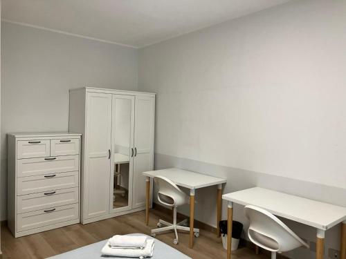 een witte kamer met een bureau en een ladekast bij Grattacielo Rooms in Turijn