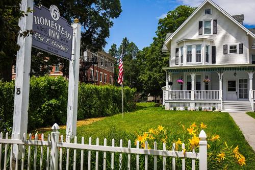 a white picket fence in front of a house at Homestead Inn in New Milford