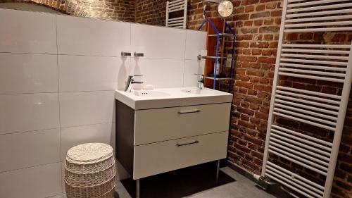 bagno con lavandino e muro di mattoni di Les Secrets du Chat a Clavier