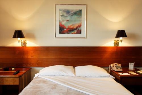 a bedroom with a bed and two desks and a phone at Hotel Diplomat in Cochabamba