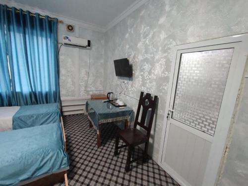 a bedroom with a bed and a table and a window at ASR HOSTEl in Andizhan