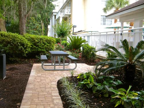 a patio with a table and bench in a garden at Palmera Inn and Suites in Hilton Head Island