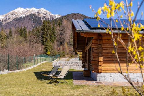 un paio di sedie sedute di fronte a una baita di tronchi di Chalet Eco-Lodge Faè a Madonna di Campiglio
