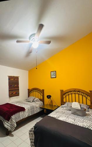 a bedroom with two beds and a ceiling fan at Casa Orquídeas Oaxaca in Oaxaca City