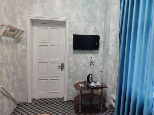 a white door with a television on a wall at ASR HOSTEl in Andizhan