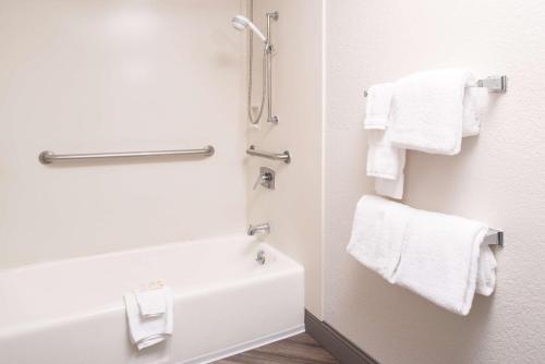 a bathroom with white towels and a bath tub at Motel 6-Red Deer, AB in Red Deer