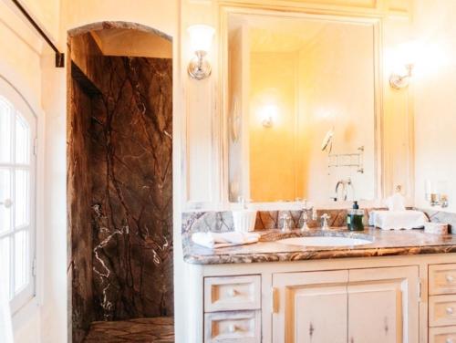 een badkamer met een wastafel en een grote spiegel bij B&B Château Légier in Fontvieille