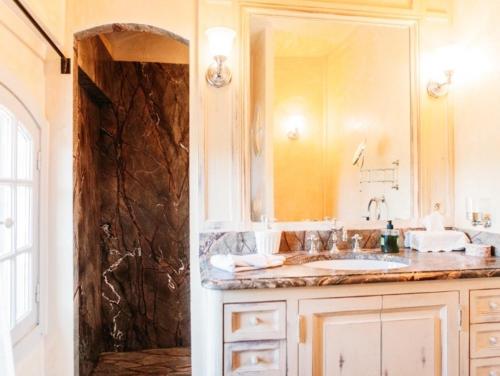 un bagno con un lavandino e un grande specchio di B&B Château Légier a Fontvieille
