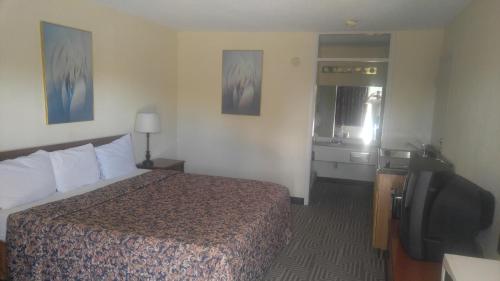 a hotel room with a bed, chair, and nightstand at Americourt Extended Stays in Kingsport