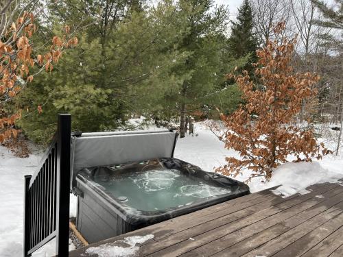 un jacuzzi sur une terrasse enneigée dans l'établissement Spa et Waterfront - Cachette du Petit Lac, à Chertsey