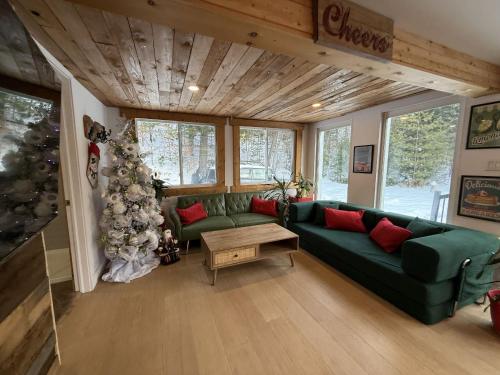 - un salon avec un canapé vert et un arbre de Noël dans l'établissement Spa et Waterfront - Cachette du Petit Lac, à Chertsey