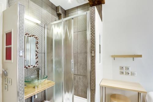 a bathroom with a glass shower with a sink at Hôtel Marie in Paris