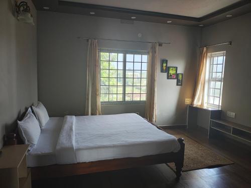 a bedroom with a bed and a large window at Coorg Ashiyana in Kushālnagar