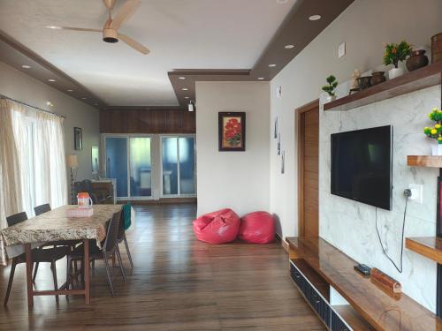 a living room with a dining table and a television at Coorg Ashiyana in Kushālnagar