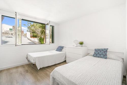 Cette chambre blanche dispose de deux lits et d'une fenêtre. dans l'établissement Villa Can Ernest, à Cala Galdana