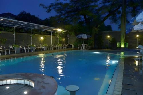 een zwembad 's nachts met tafels en stoelen bij Kedaton Hotel in Bandung