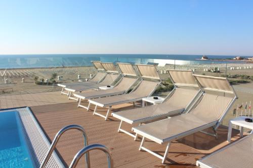 a row of lounge chairs next to a swimming pool at Hotel Monaco in Caorle