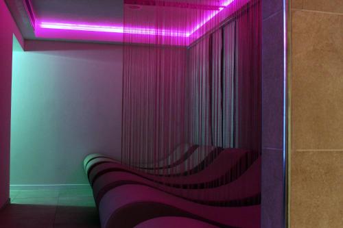 a bench in a room with a pink light at Hotel Monaco in Caorle