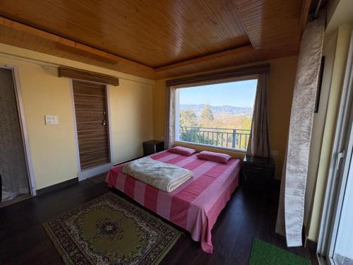 a bedroom with a bed and a large window at Tapas in Champawat