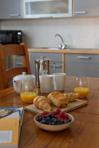 a table with croissants and a plate of fruit and orange juice at Cozy 3BR escape near Edinburgh centre in Edinburgh