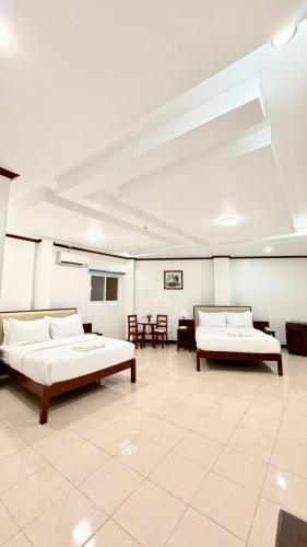 a large room with two beds and tables in it at SANJH Island Hotel powered by Cocotel in Roxas