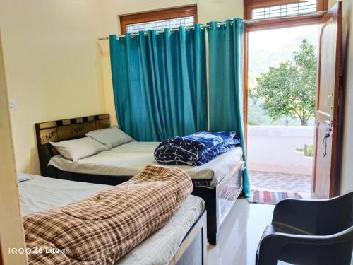 a room with two beds and a window with at Himadri Homestay Sari Devriyatal in Sari