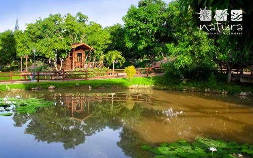 a pond in a park with a house in the background at Natura Reservado - Hoteles Natura in Anapoima