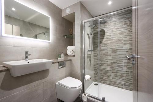 une salle de bains avec toilettes, lavabo et douche dans l'établissement All Saints Resort, à Bury St Edmunds